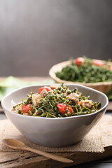 Northern Thai food (Kaeng Sa Lae), Spicy soup Broussonetia Kurzii with pork and tomatoes in a bowl on wooden background, Seasonal food in North Thailand