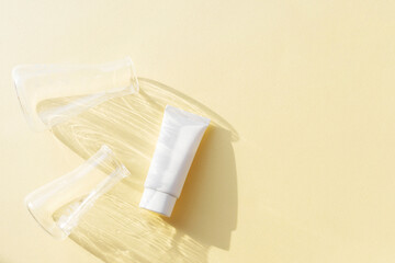 white cosmetic tube on a beige background with medical flasks and reflections. Cosmetics making concept. Copy space