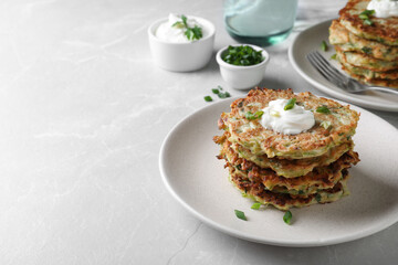 Delicious zucchini fritters served on light table, space for text