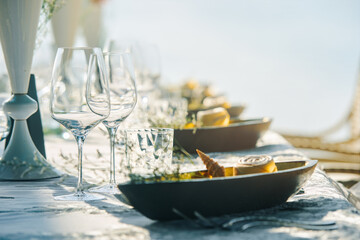 Festive table decor wine glasses and table setting in on the beach.. Preparing for an open-air...