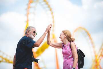 happy senior friend couples enjoy in amusement water park with icecream and photography. Two olders lover togetherness for holiday at theme park.