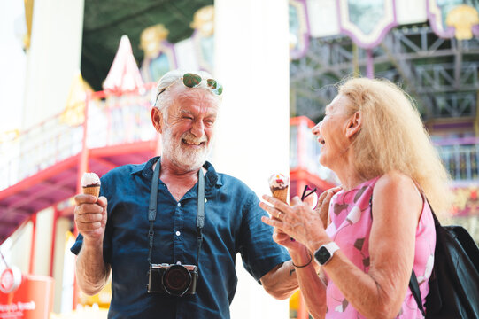 happy senior friend couples enjoy in amusement water park with icecream and photography. Two olders lover togetherness for holiday at theme park.