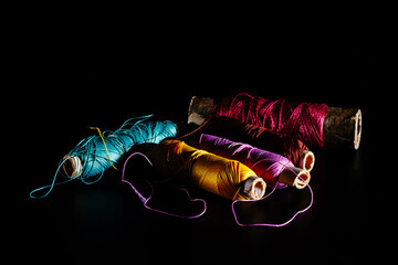 Bright silk multicolored threads isolated on a black background. Beautiful background for sewing and needlework with spools of thread