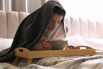 Woman with plaid doing inhalation above bowl on bed
