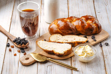 Side view on sweet raisins bun pigtail bread on the decorated wooden background