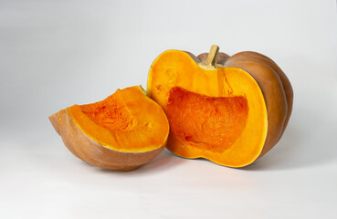 Bright orange pumpkin cut into pieces on a light background