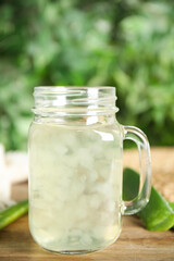Fresh aloe drink in mason jar and leaves on wooden table