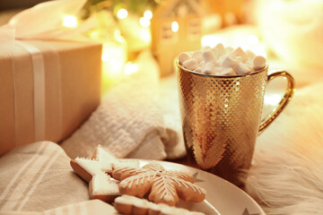 Cup of hot drink with marshmallows and Christmas cookies at table
