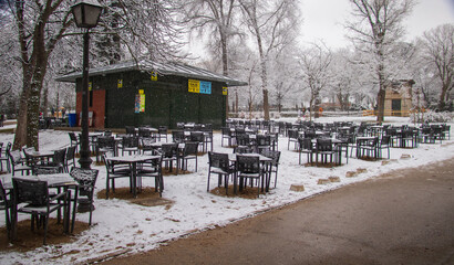 a restaurant bar outdoor terrace is closed because of lock down on the city with empty chairs and tables in cold winter snowfall day