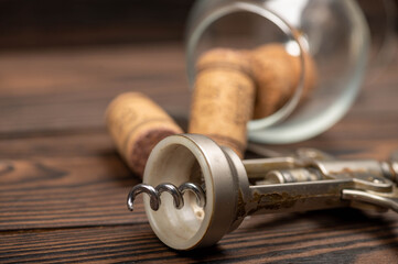 Corkscrew and corks from wine bottles on a wooden table.