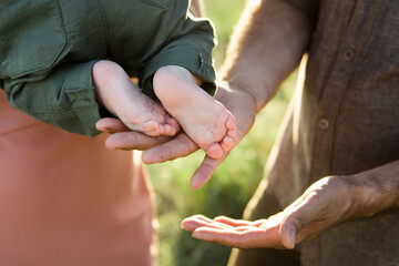 The legs of the newborn in the hands of mom and dad close up.