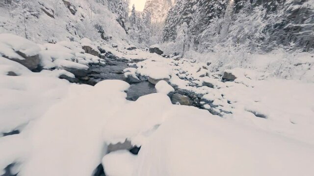 Water From Cascade du Rouget Flowing Between Rocks Covered With Snow In Winter. - FPV, aerial
