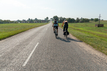 Obraz premium Grodno, Belarus, 16 July 2020: Two cyclists ride on an asphalt road. Cycling around the countryside. Cycling as a way of spending time and a healthy lifestyle.