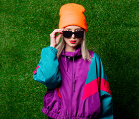 Woman in 80s sportsuit and glasses on green grass background