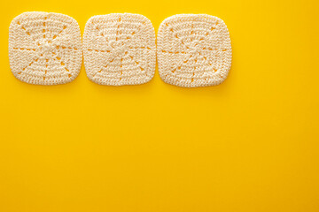 黄色い背景に置いた四角形のレースのコースター３つの構成