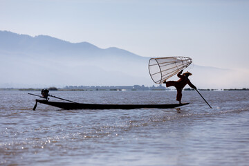 MandalaFisherman silhouette balancing net on a boat Inle lake, Myanmar