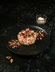 salad with ham, potatoes, pomegranate seeds and walnuts. Salad pomegranate bracelet on dark background