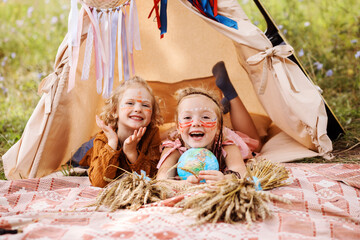Cheerful girls with native american makeup have fun inside wigwam in summer. © Natalia