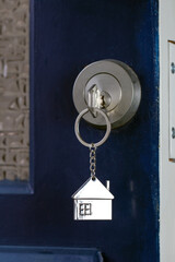 Open door to a new home with key and home shaped keychain. Mortgage, investment, real estate, property and new home concept