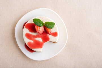 Top view cheesecake garnished with fresh strawberries and berry syrup.