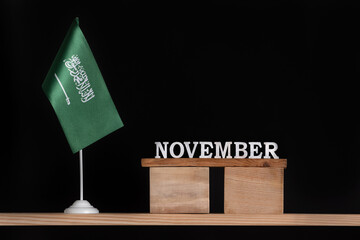 Wooden calendar of November with Saudi Arabia flag on black background. Dates of Saudi Arabia in November