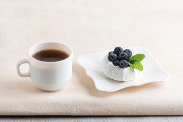 Cup of coffee next to berry dessert. Fresh blueberry meringue cake and tea