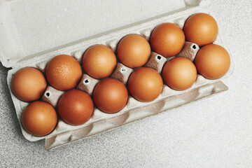 Culinary class in a kitchen. A dozen of tinted brown chicken eggs in an open carton box on the...