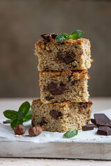 Oatmeal squares with chocolate, nuts, pieces of chocolate and mint, light concrete background. Diet bars. Healthy bakery for breakfast or dessert.