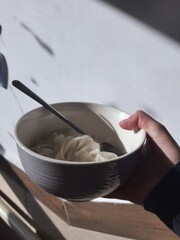 a hand holding a bowl of noodles