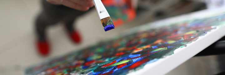 Close-up of persons hand creating abstract painting on canvas combine different styles. Picture with mixed colours. Creative and talented young male artist. Masterpiece and modern art concept