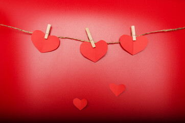 Red paper origami hearts on craft rope isolated on red background.