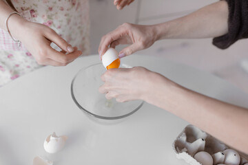 Closeup of a pair of hands cracking an egg into a glass bowl. Cook at home. lgbt family