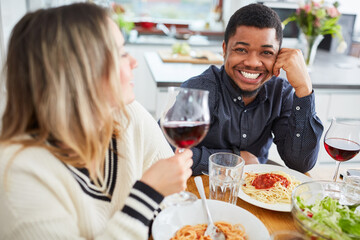 Happy friends at the table with red wine while eating together