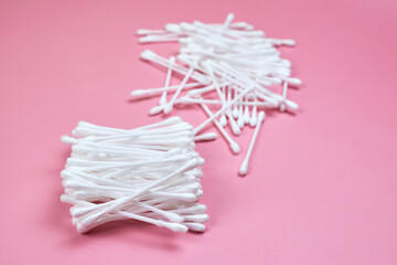 White cotton ear buds on a pink background.