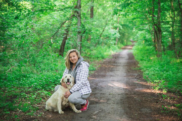 attractive blonde hugging a dog on the trail in the forest