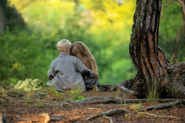 A little boy and a girl embrace in the summer forest. First love.