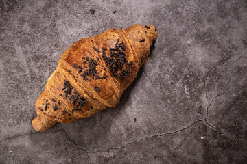 Croissant with chocolate chips on a gray mottled background