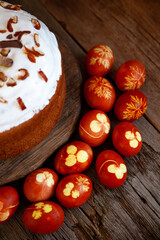 Easter cake and colored eggs. Rustic food on a wooden table. Egg colored with onion peel. Clover and dill leaves pattern. Classic food for the Easter holiday