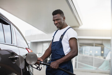 Petrol station, transportation and refueling concept. Handsome young black man, gas station worker,...