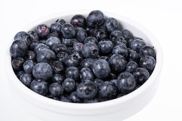 white bowl full with fresh blueberries on white background 