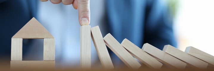 Businessman built house from wooden blocks. Real estate accident insurance concept