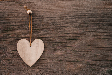 Valentine's Day background. Brown natural boards in grunge style with one wooden decorative hearts. Top view. Surface of table to shoot flat lay. Concept love, romantic relation. Copy space for text.