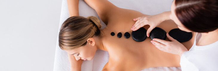 Top view of young woman getting hot stone massage in spa salon, banner