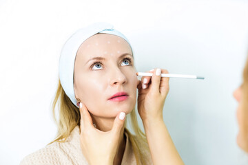 Woman at a beautician's appointment. A specialist examines it and makes markings with a special pencil. Non-surgical face lifting. SMAS lifting ultrasonic. Facelift