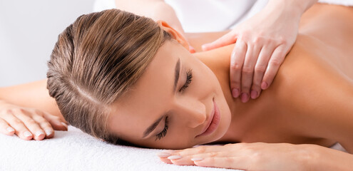 Masseur massaging pleased woman on massage table in spa salon, banner