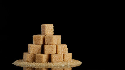 Demerara brown sugar cubes on black background 
