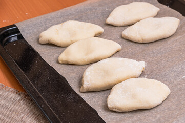 Fototapeta na wymiar Russian pies formed from raw dough. Homemade baking