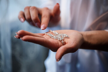 The bride holds earrings in her hand on her wedding day. Jewelry for a holiday for the newlyweds