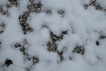 snow covered pavement with gravel
