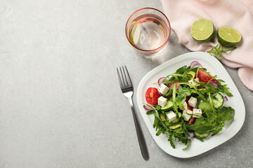 Delicious salad with feta cheese, arugula and vegetables on grey table, flat lay. Space for text